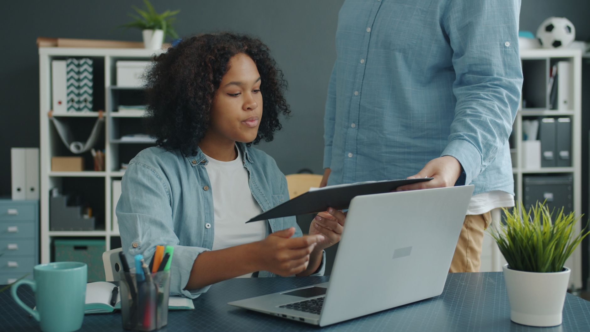 Dos profesionales colaborando en una oficina con una laptop y documentos.