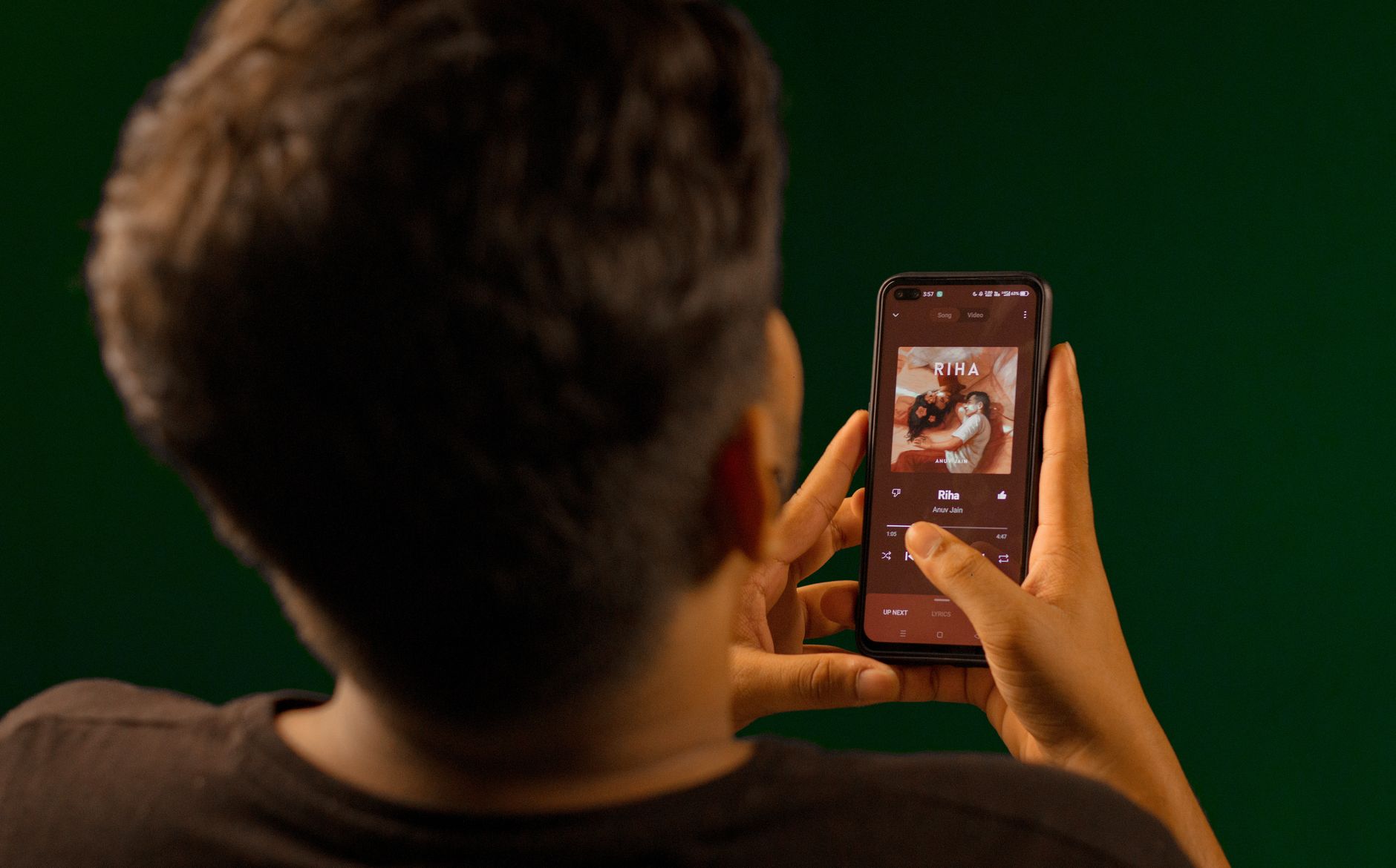 A person using a smartphone to stream music from a streaming service app indoors.