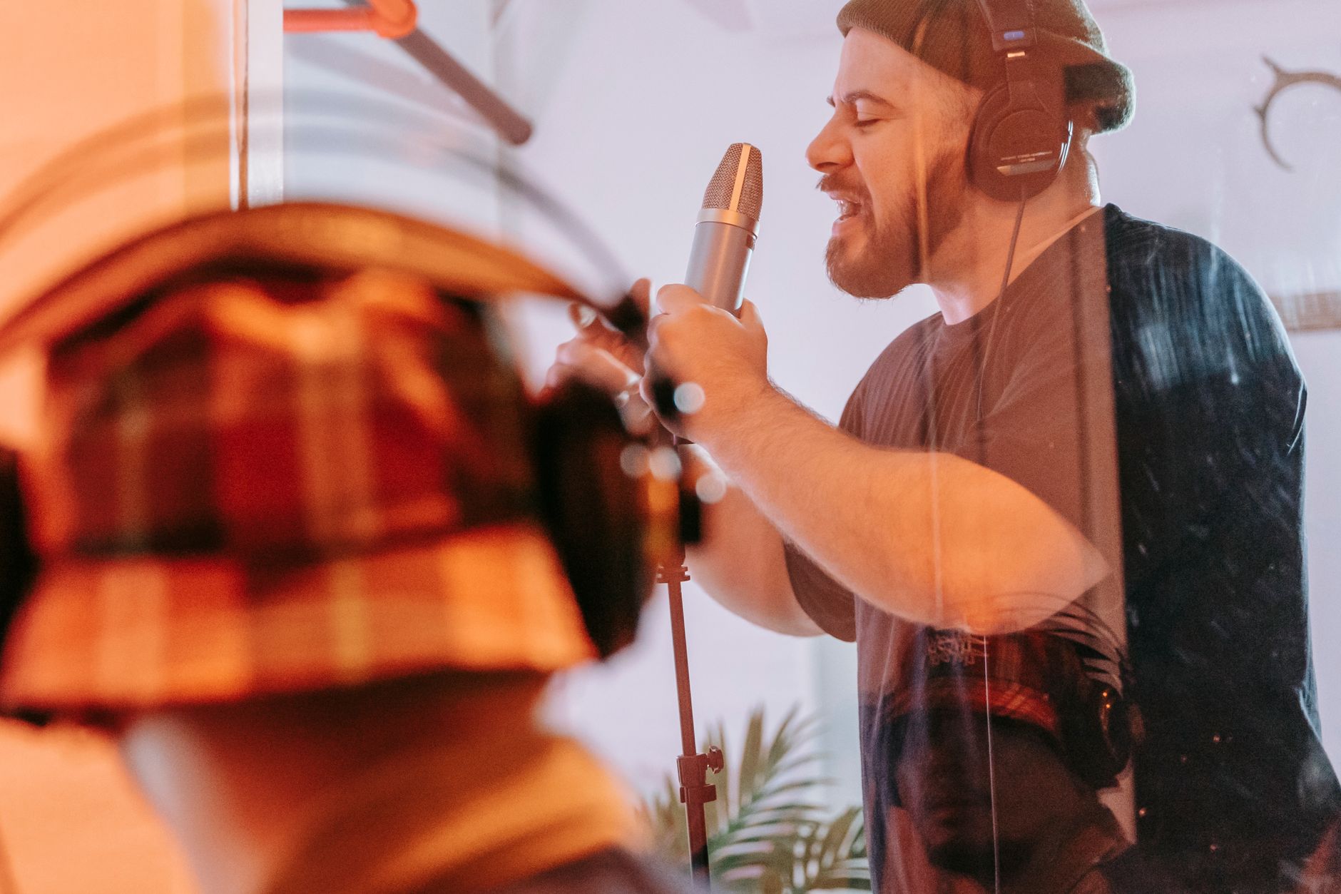 Cantante adulto grabando voces en un estudio, con audífonos y frente a un micrófono.