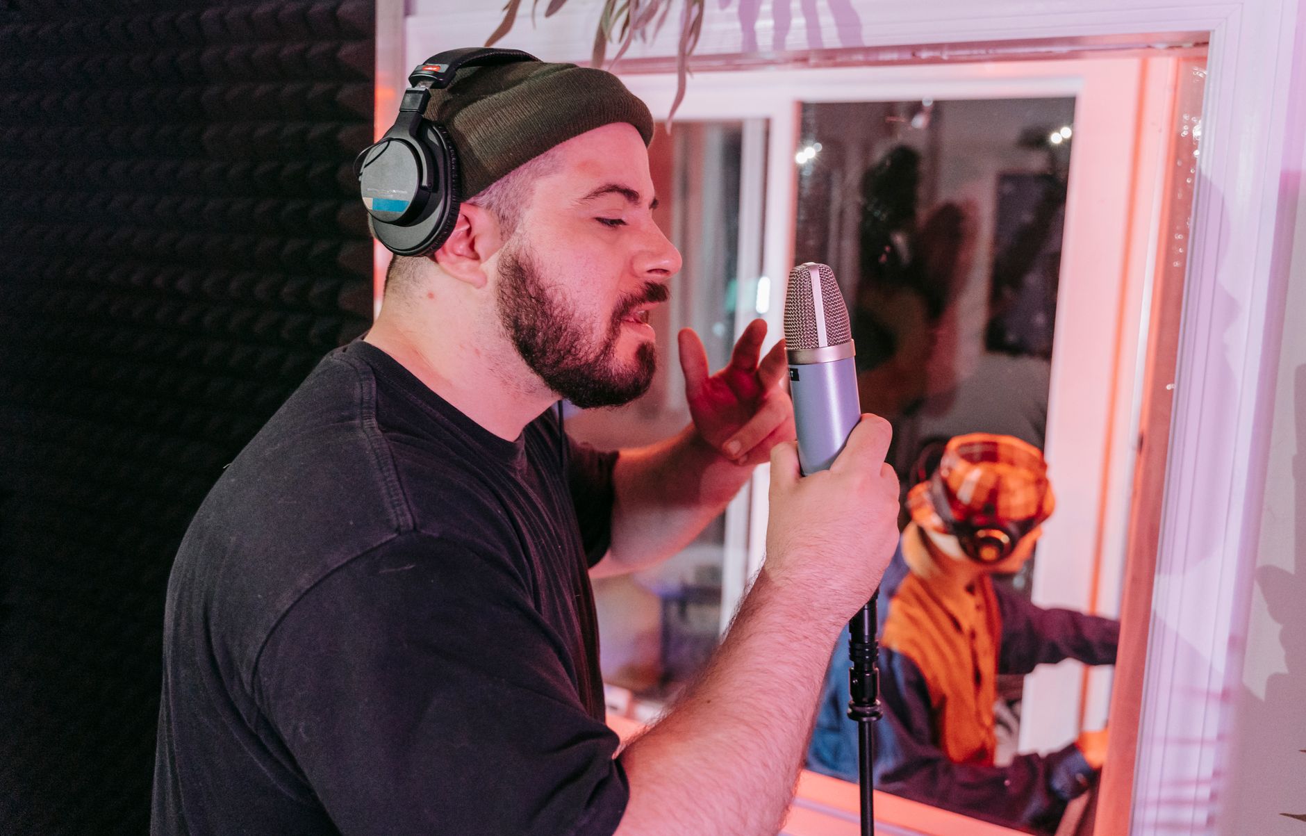 Adult male singer recording a song in a professional music studio with headphones and microphone.
