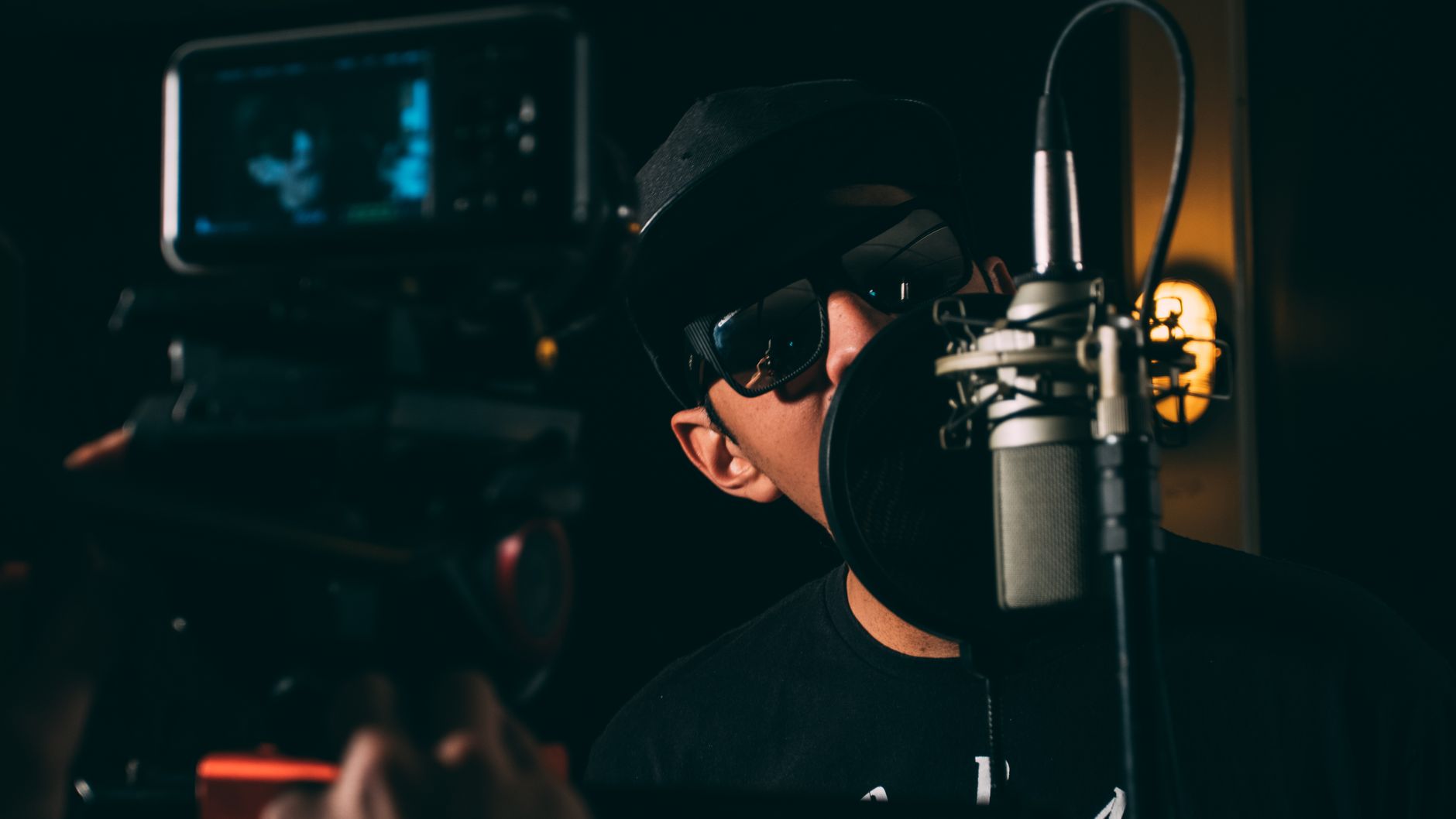 Un artista de hip-hop graba voces en un estudio oscuro y atmosférico.