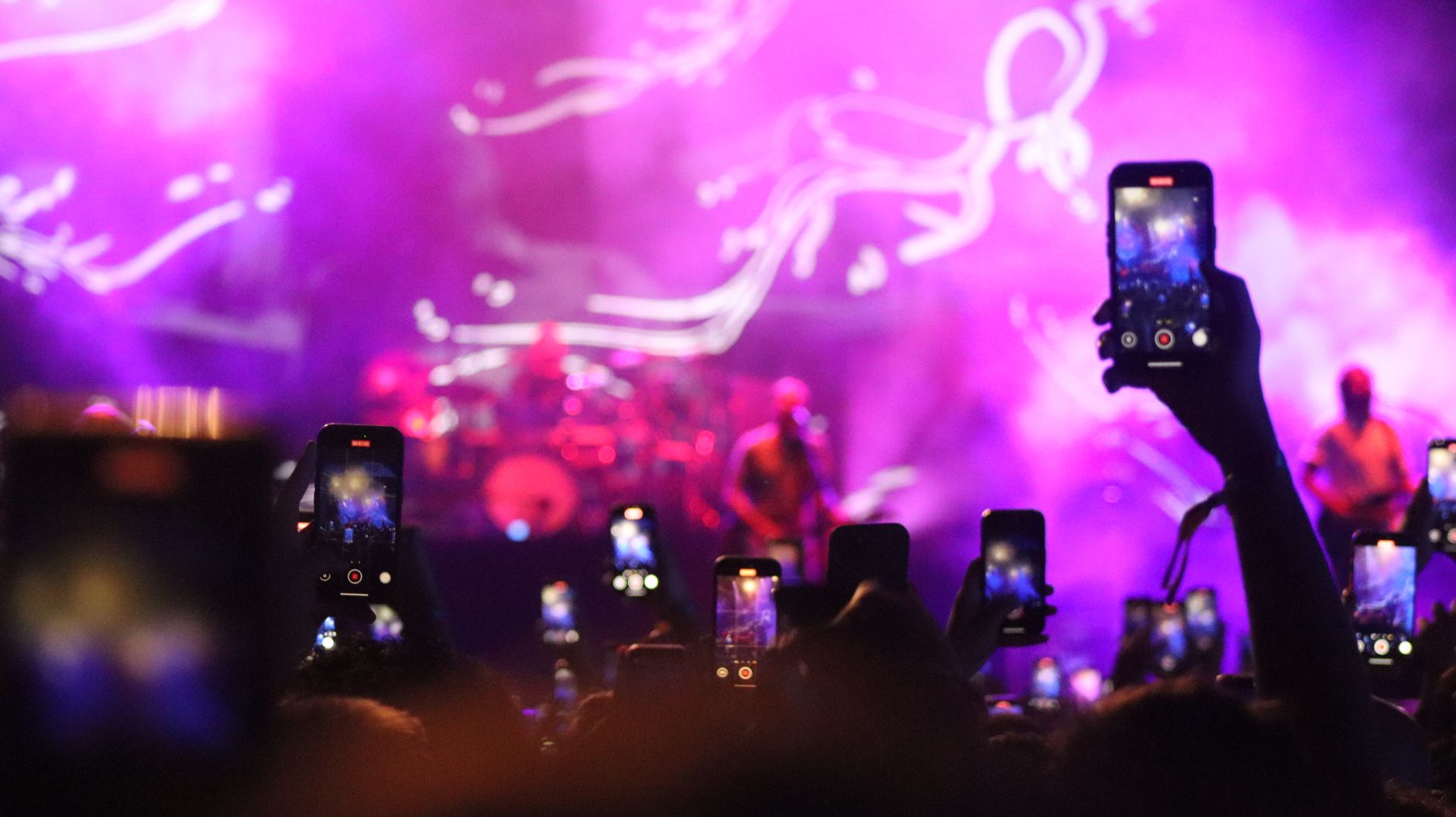 Exciting live music concert with audience capturing moments on smartphones.
